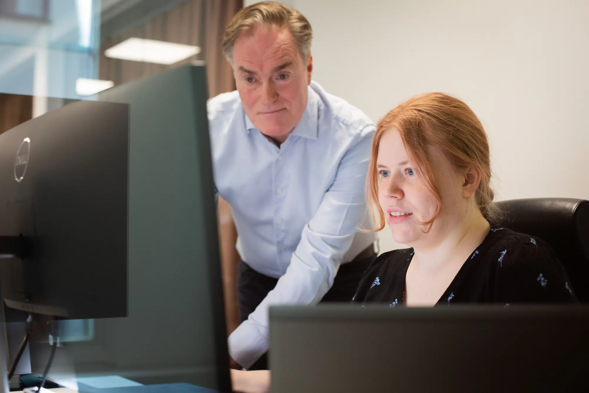 Two people at a workstation reviewing data on screen